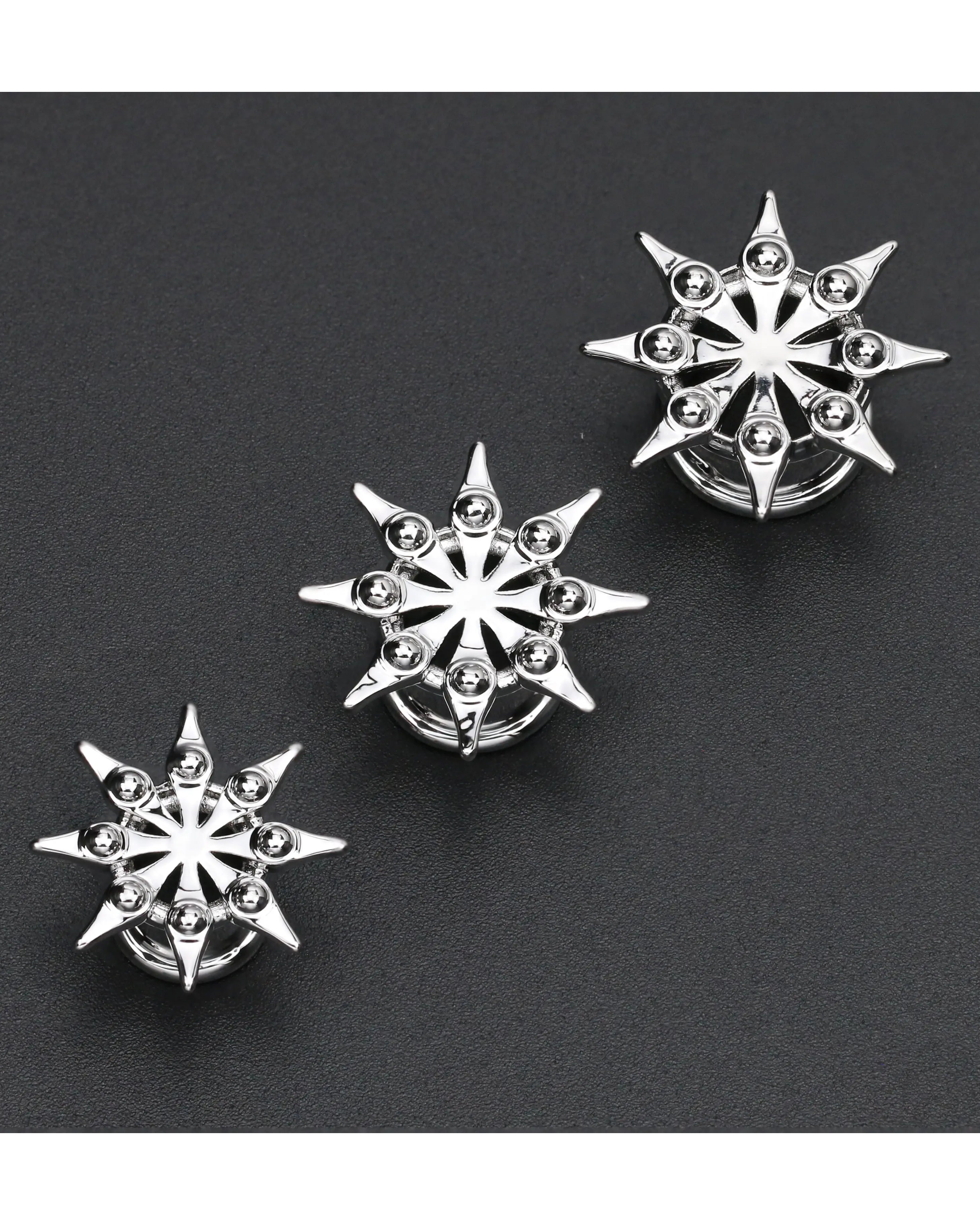 Three silver star-shaped earrings on a black background