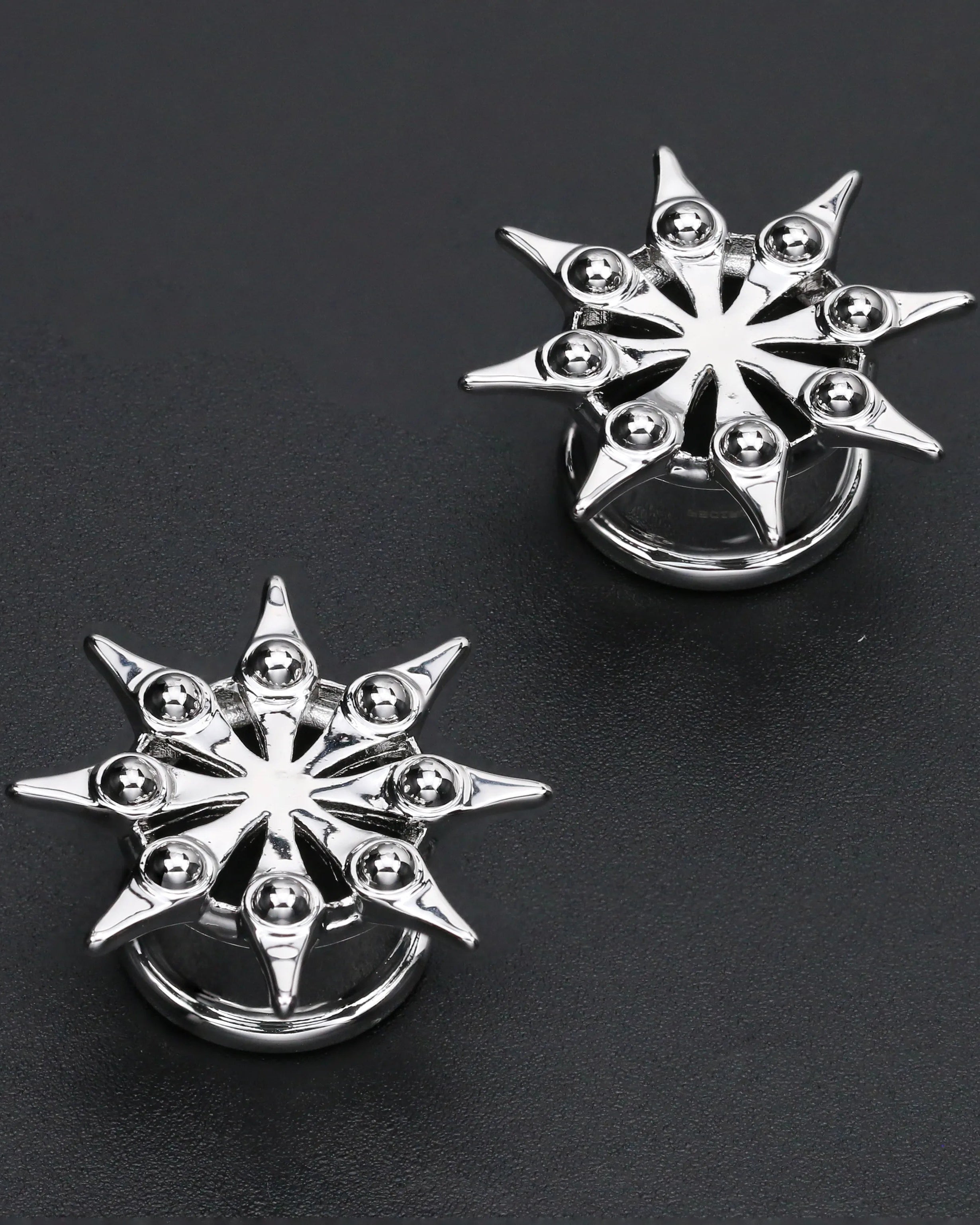 Pair of silver star-shaped earrings on a black background
