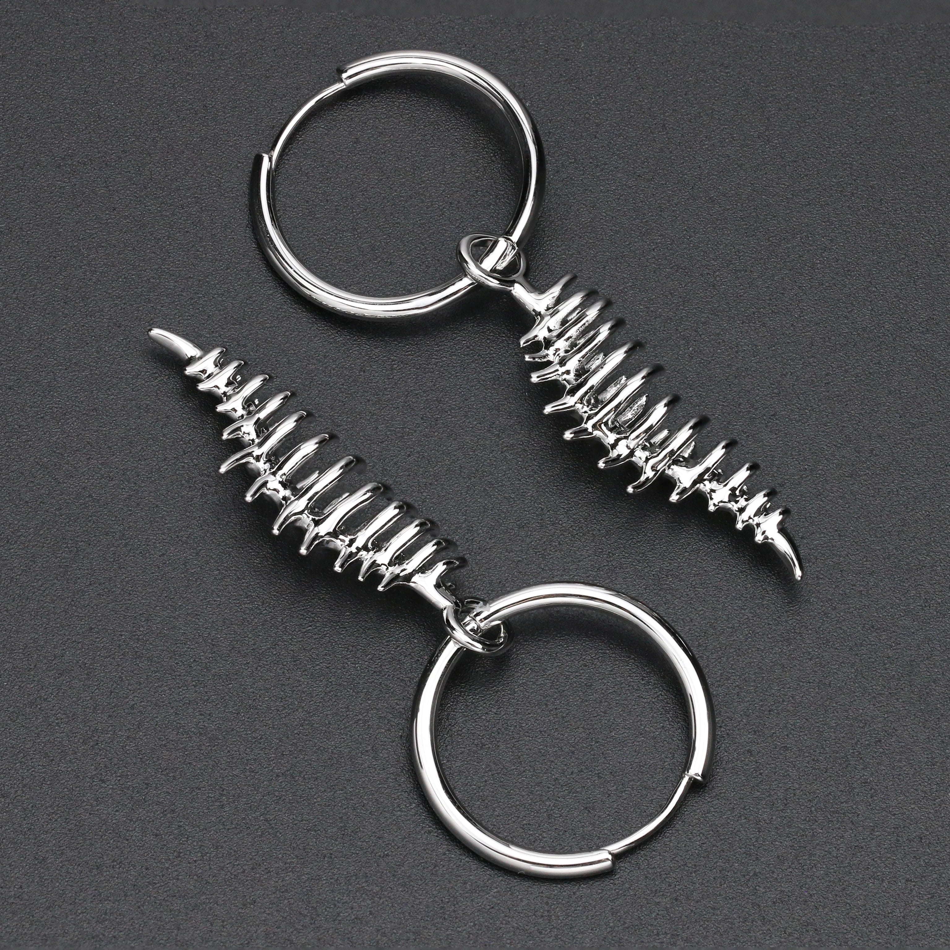 Two silver keychains with spiral designs on a dark gray background