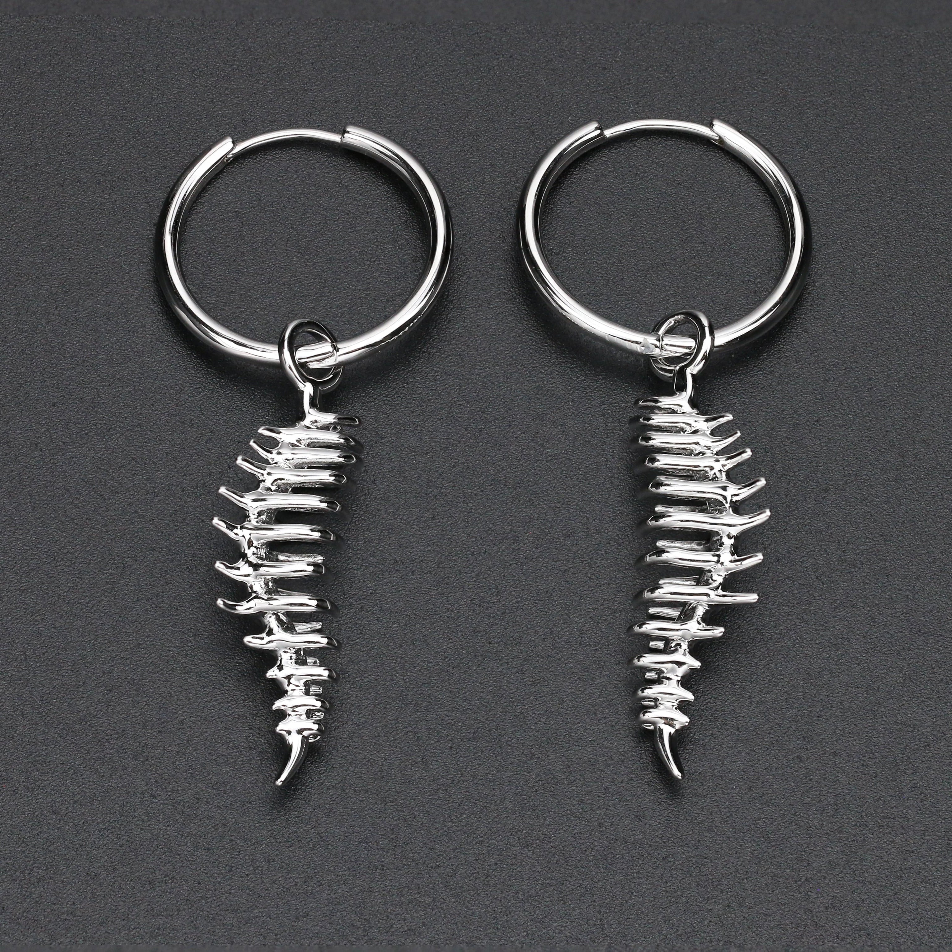 Pair of silver skeleton keychain earrings on a dark gray background